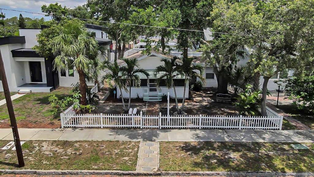 A white cottage with a screened-in front porch, palm trees, and a brick walkway — 3829 2ND AVENUE N, ST PETERSBURG, FL