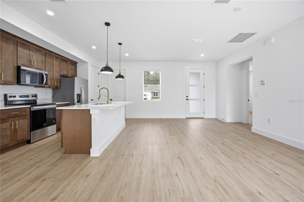 A modern kitchen with brown cabinets, stainless steel appliances, and a central island — 1 OAK TRAIL, OCALA, FL