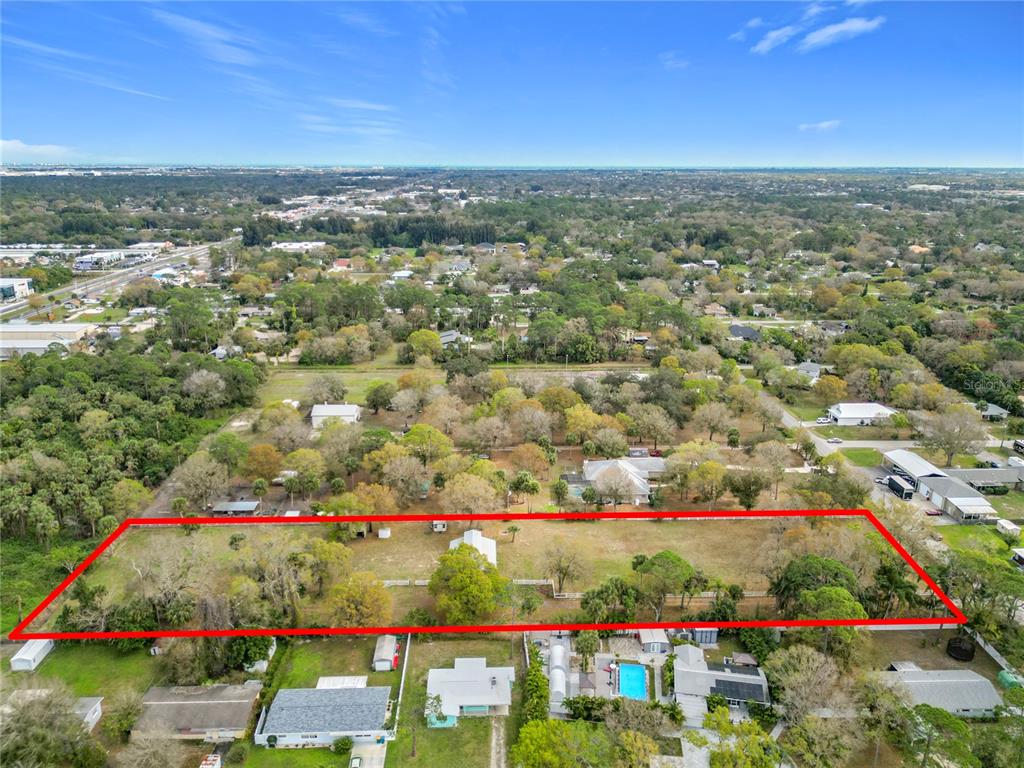 An aerial view shows a large, rectangular residential lot outlined in red with scattered trees — 3900 MIAMI AVENUE, MELBOURNE, FL