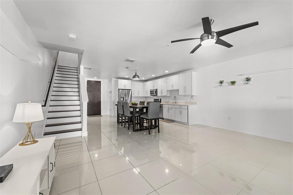 A modern open-concept kitchen and living area with white cabinetry, tile flooring, and a staircase — 436 W SWOOPE AVENUE, WINTER PARK, FL