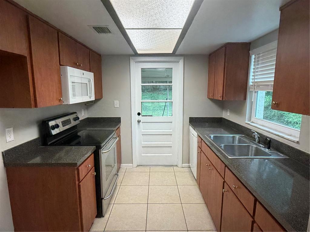 A kitchen features wood cabinets, dark countertops, a white door, and tiled flooring — 11510 VALENCIA DR UNIT 2, SEFFNER, FL