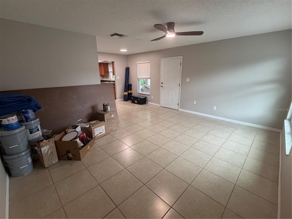 An interior room features light-colored tile flooring, a ceiling fan, and boxes stacked near a wall — 11510 VALENCIA DR UNIT 2, SEFFNER, FL