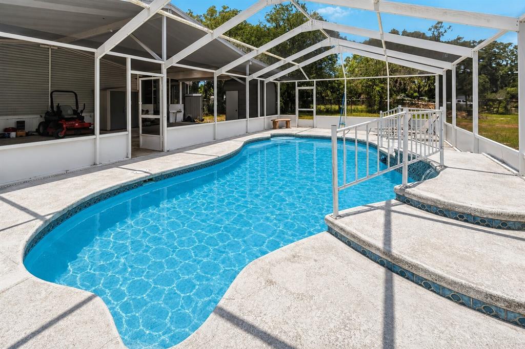 A swimming pool with a screened-in enclosure and a raised concrete deck with stairs — 12104 WOODSIDE DRIVE, RIVERVIEW, FL