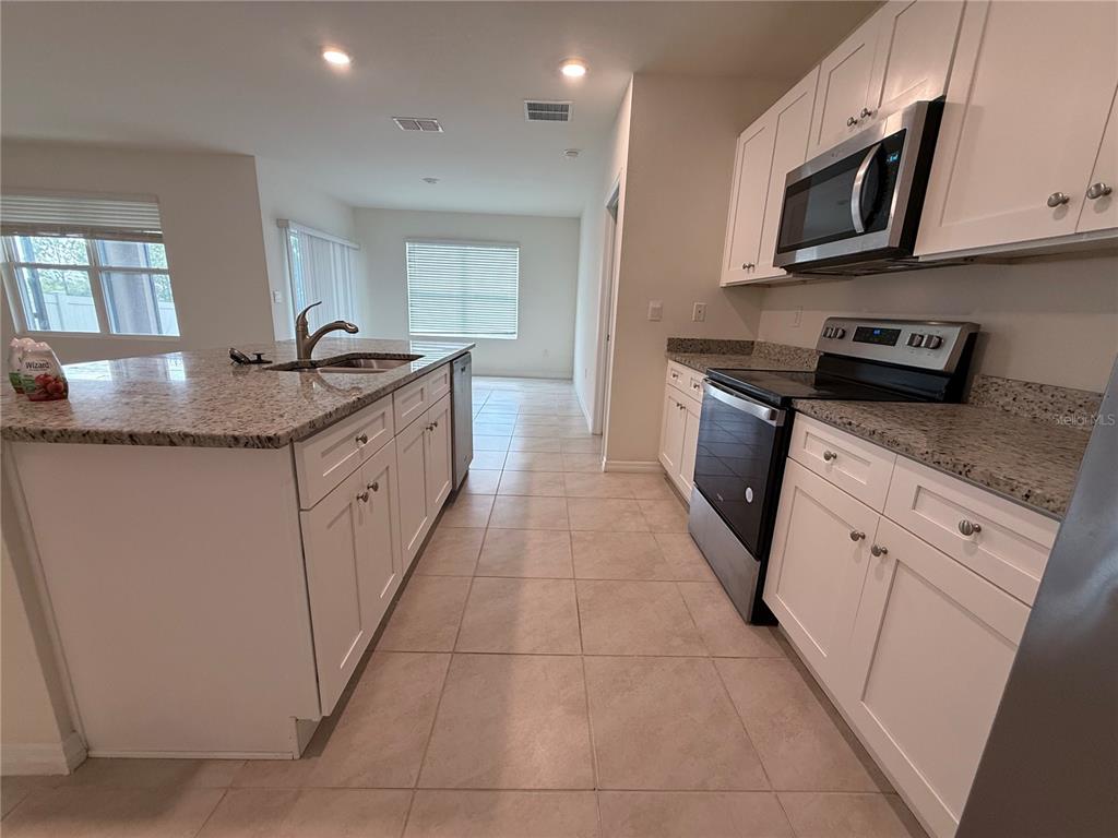 An empty room with tile flooring, a sliding glass door, and a window with blinds — 1344 SUGARWOOD STREET, DAVENPORT, FL