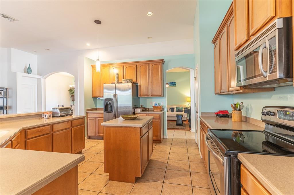 A kitchen with wood cabinets, stainless steel appliances, a center island, and tile flooring — 2539 CENTENNIAL FALCON DRIVE, VALRICO, FL