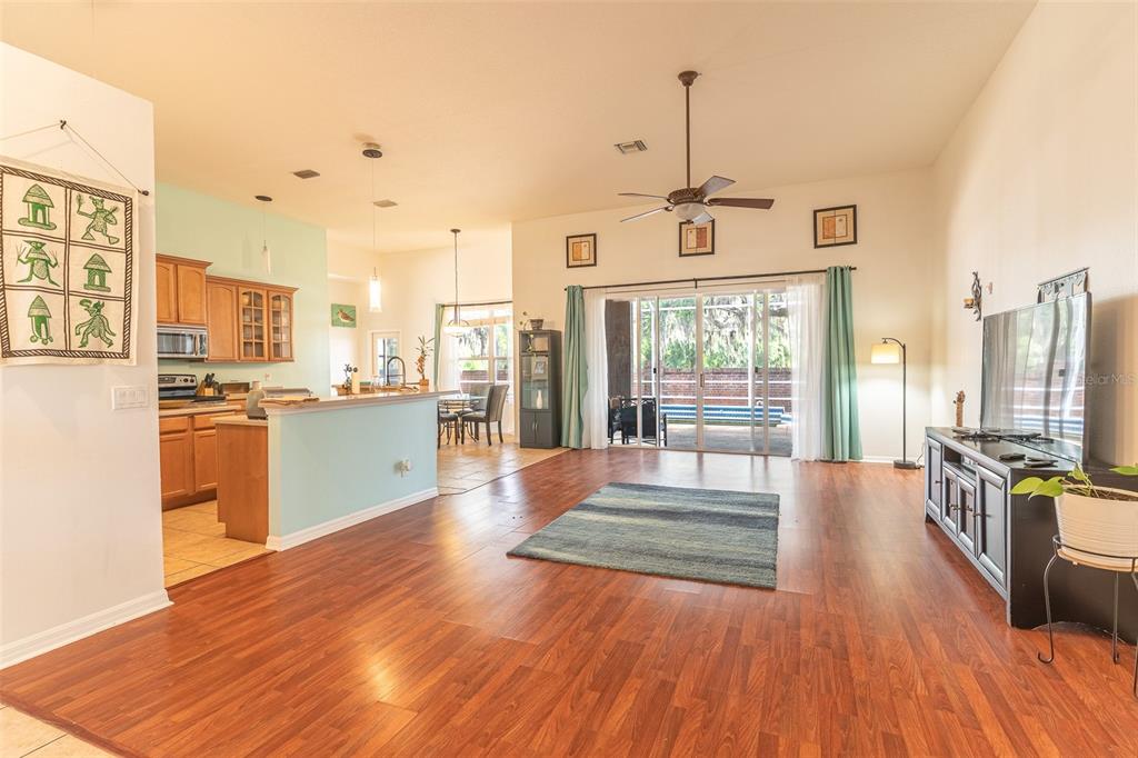 A living room with wood floors, a kitchen island, and sliding doors leading to a patio — 2539 CENTENNIAL FALCON DRIVE, VALRICO, FL