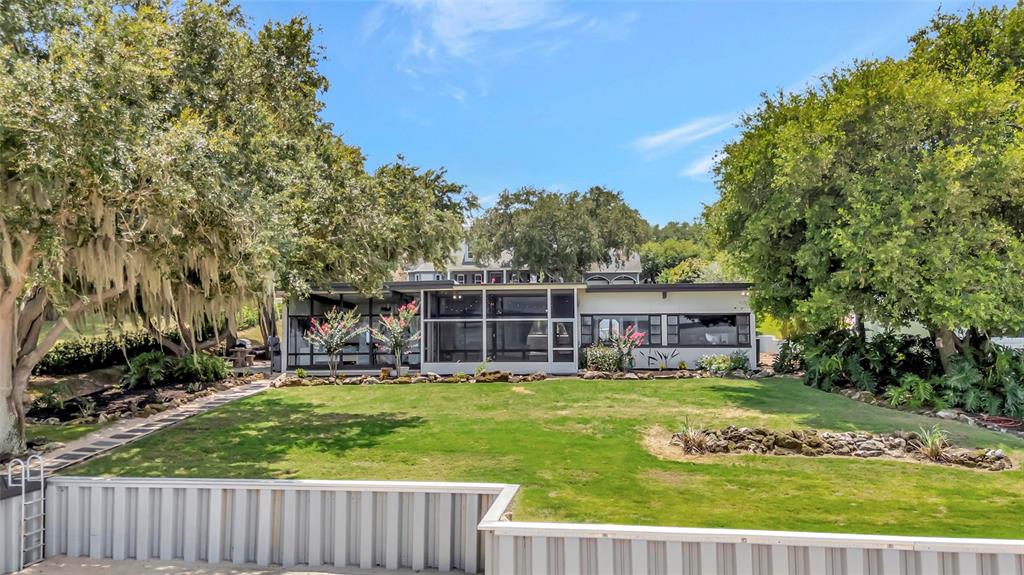 A single-story house with a screened porch sits behind a grassy lawn and bulkhead — 11900 ELBERT STREET, CLERMONT, FL