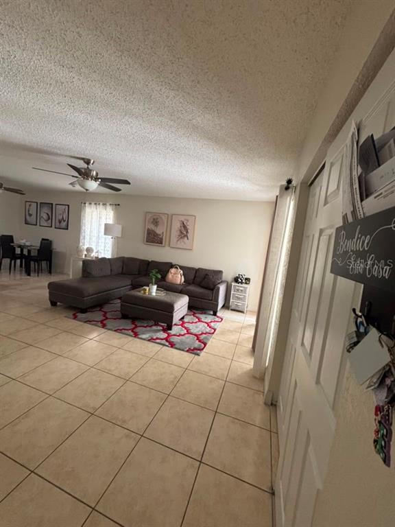 A living room features a gray sectional sofa, a patterned rug, and tile flooring — 7310 BAJA COURT, TAMPA, FL