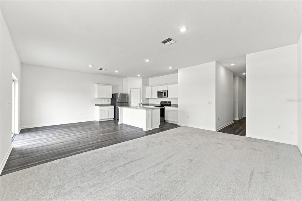 An open-concept kitchen and living area features white cabinetry, a center island, and mixed flooring — 8373 MARGO ANN STREET, BROOKSVILLE, FL