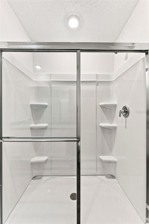 A walk-in shower with white walls, built-in shelving, and a glass sliding door — 8373 MARGO ANN STREET, BROOKSVILLE, FL