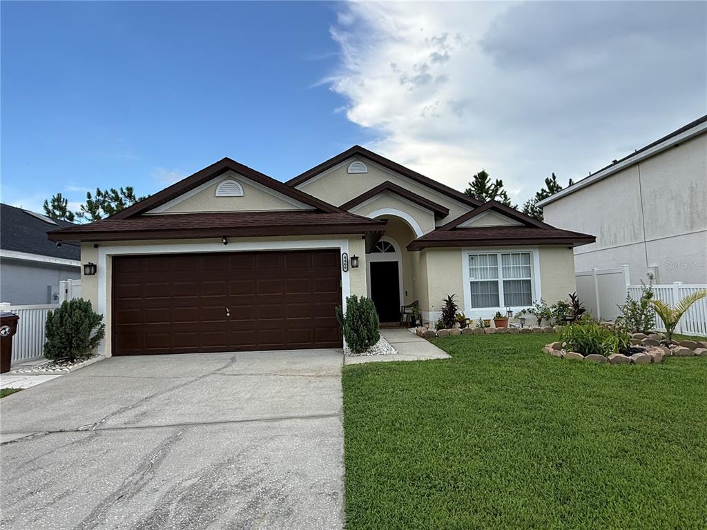 A single-story house with a brown garage door, tan stucco siding, and a brown roof — 4466 GREAT HARBOR LANE, KISSIMMEE, FL