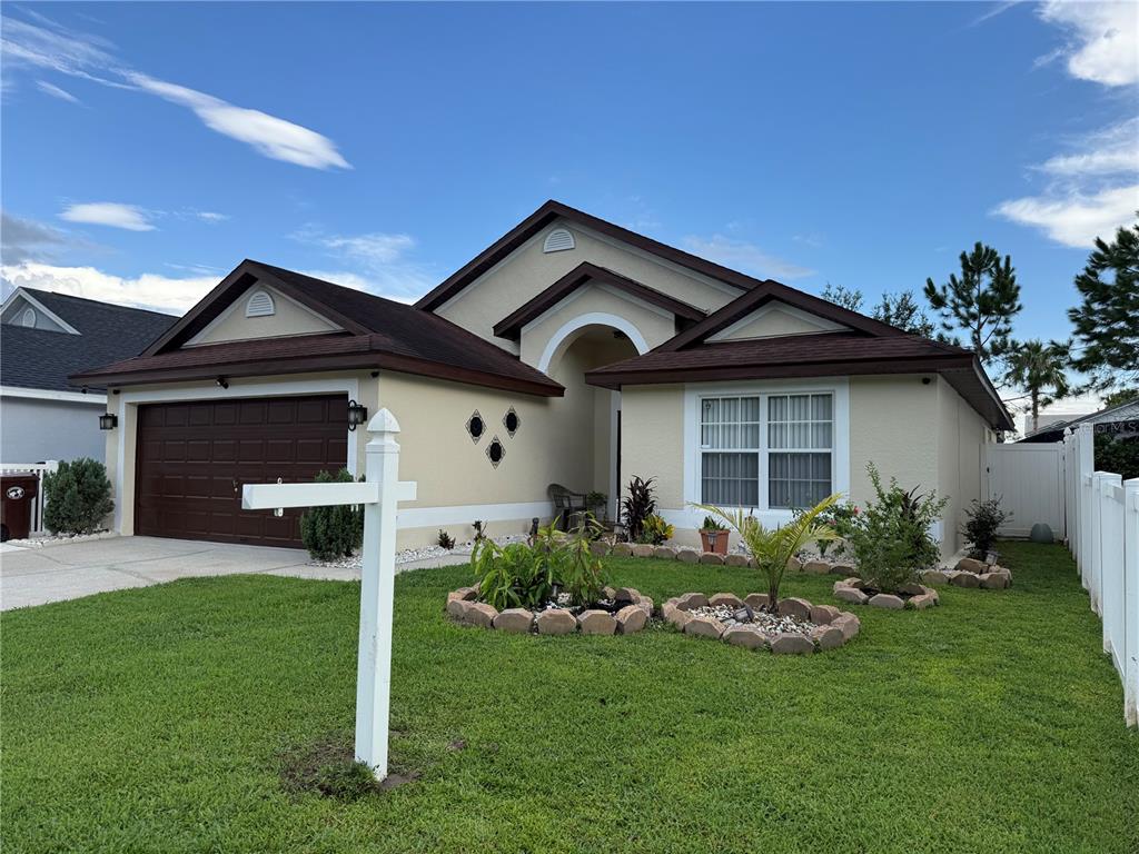 A single-story house with a brown garage door, tan stucco exterior, and a front lawn — 4466 GREAT HARBOR LANE, KISSIMMEE, FL