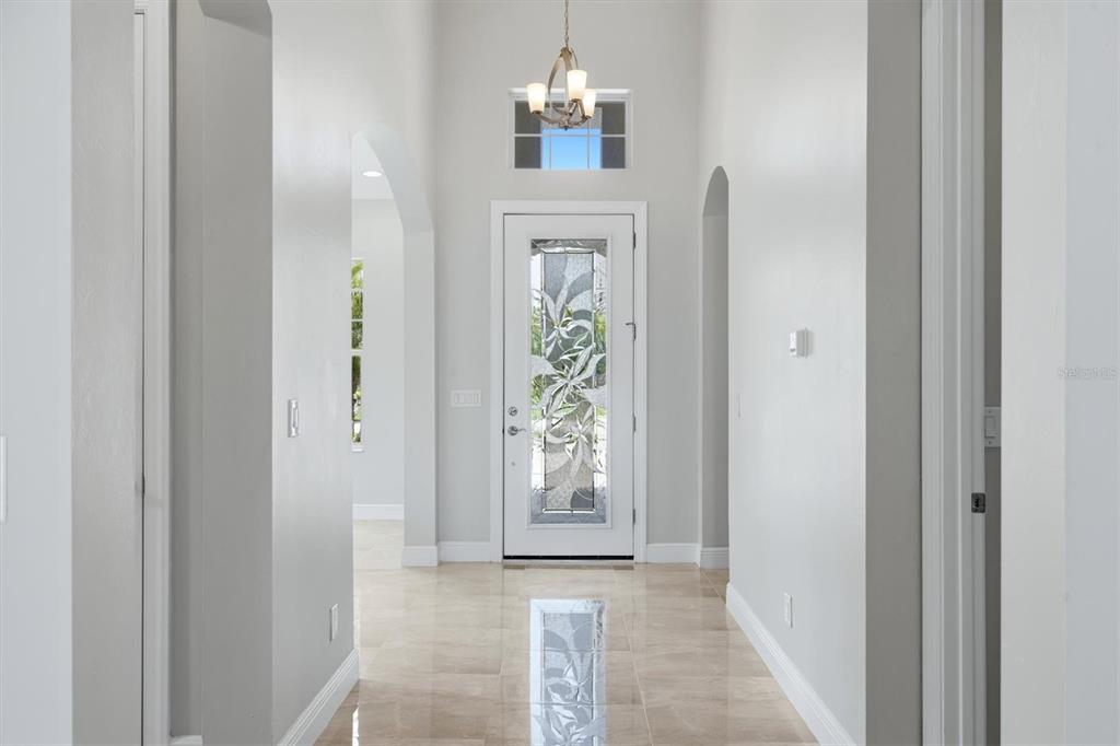 A bright entryway features a decorative glass front door, tile flooring, and a chandelier — 5109 TIDEWATER PRESERVE BLVD, BRADENTON, FL