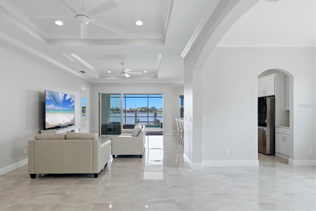 A bright living room with tile floors, a tray ceiling, and a view of water — 5109 TIDEWATER PRESERVE BLVD, BRADENTON, FL