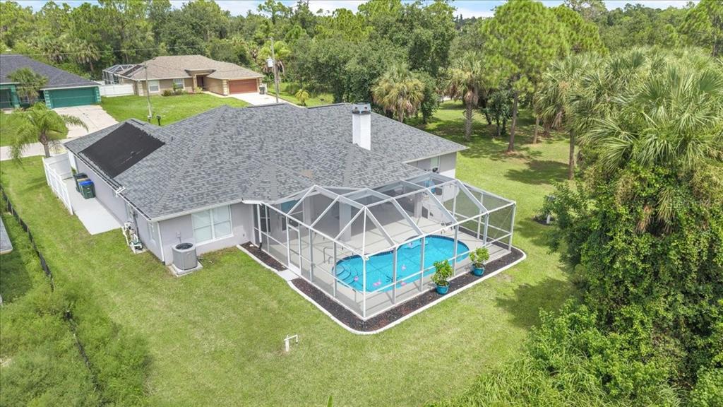 An aerial view of a house with a shingled roof, pool cage, and backyard landscaping — 1240 NORA LANE, NORTH PORT, FL