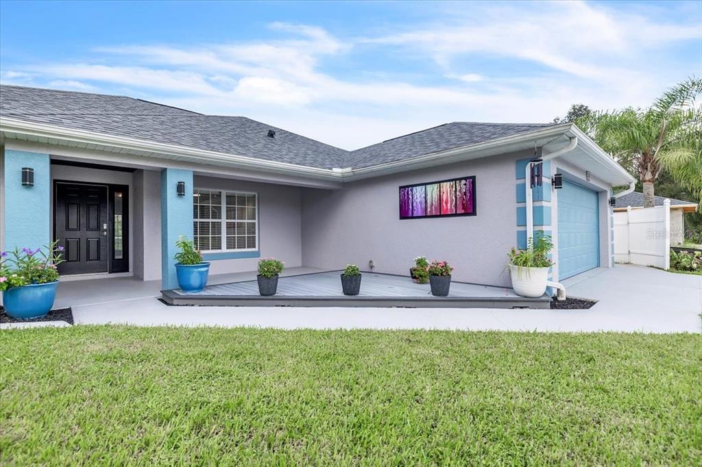 The exterior of a single-story house features a gray facade, blue accents, and a front porch — 1240 NORA LANE, NORTH PORT, FL
