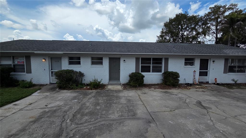 A single-story white brick apartment building with a cracked concrete driveway in front — 927 S BUENA VISTA DRIVE, LAKE ALFRED, FL