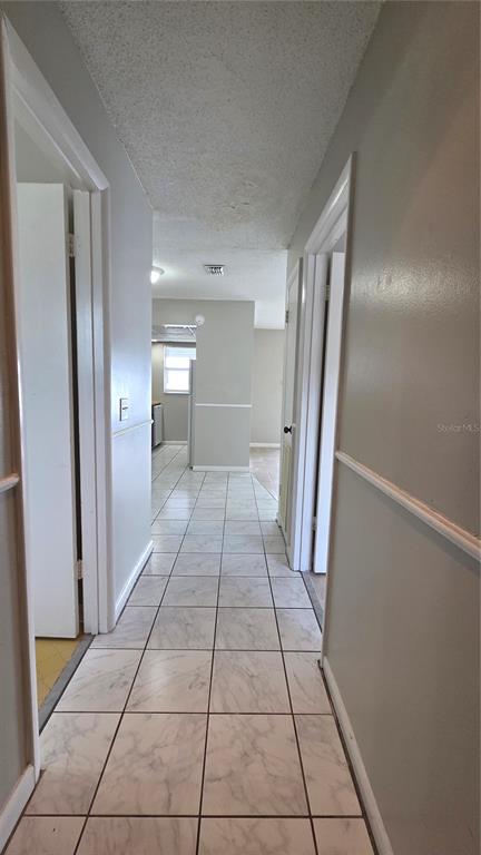 A hallway with white tile flooring leads toward an open kitchen area — 927 S BUENA VISTA DRIVE, LAKE ALFRED, FL
