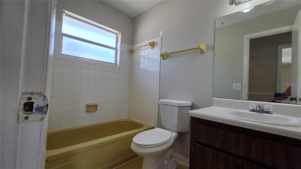 A bathroom features a yellow bathtub, a white toilet, and a vanity with a mirror — 927 S BUENA VISTA DRIVE, LAKE ALFRED, FL