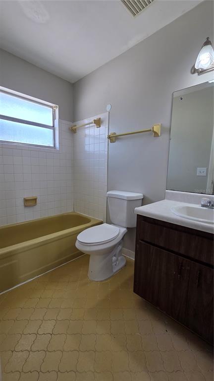 A bathroom features a yellow bathtub, a white toilet, a vanity, and a wall mirror — 927 S BUENA VISTA DRIVE, LAKE ALFRED, FL