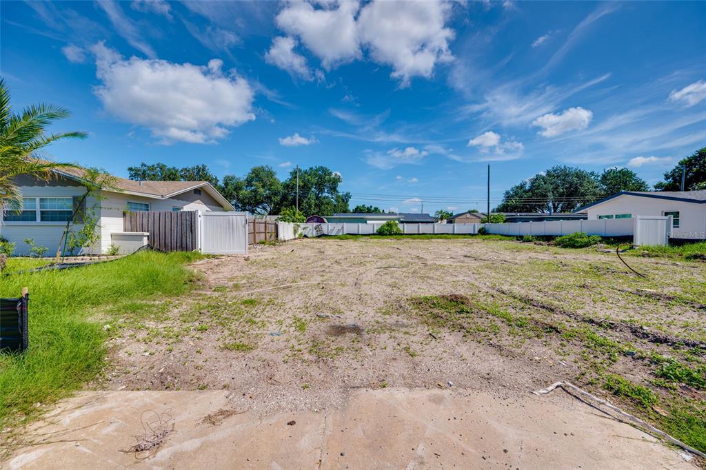 A vacant, cleared residential lot features patches of grass and a white vinyl fence — 13945 TRINIDAD DRIVE, SEMINOLE, FL