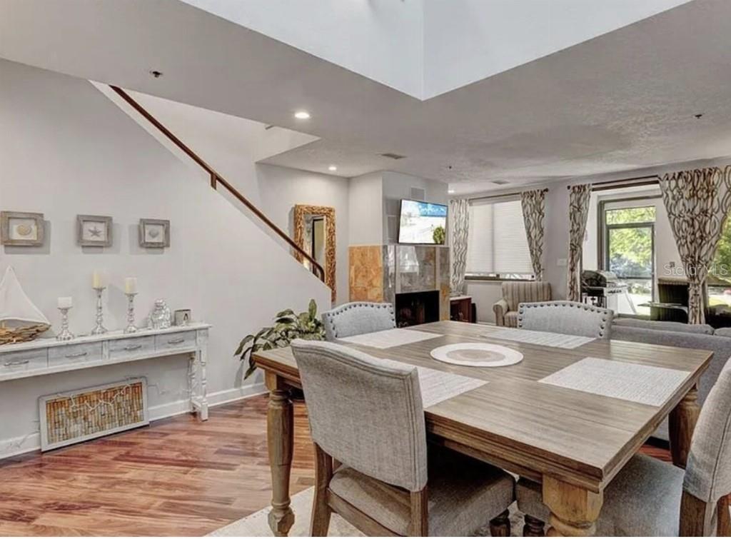 A dining room with a wooden table, upholstered chairs, a staircase, and a stone fireplace — 1926 HARBOURSIDE DRIVE UNIT 1302, LONGBOAT KEY, FL
