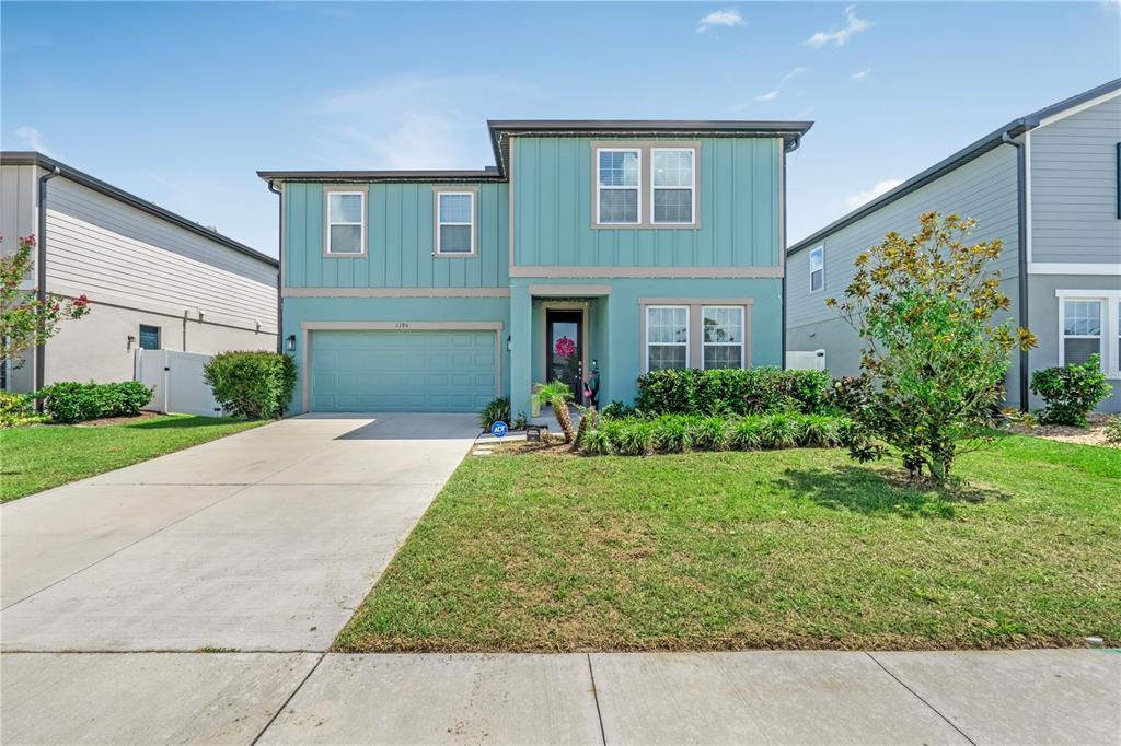 A two-story teal house with a two-car garage and a front lawn — 1195 PEARL TREE ROAD, DELTONA, FL