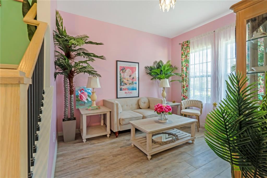 A living room features pink walls, a beige sofa, a coffee table, and tropical decor — 1195 PEARL TREE ROAD, DELTONA, FL
