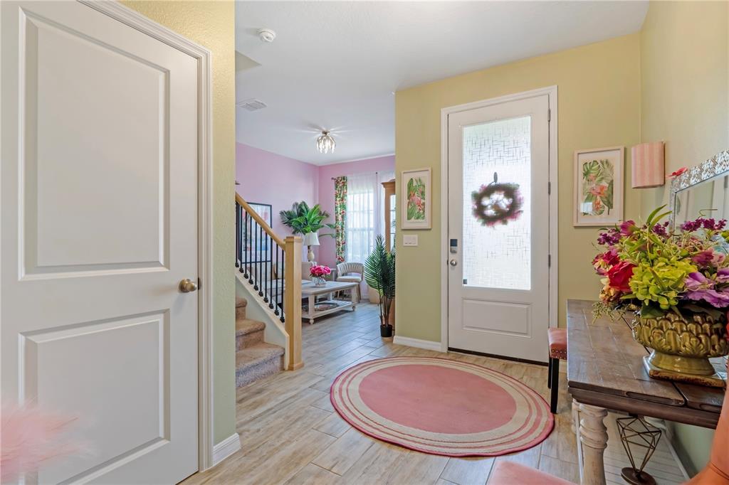 An entryway with light green walls, tile flooring, a staircase, and a front door — 1195 PEARL TREE ROAD, DELTONA, FL