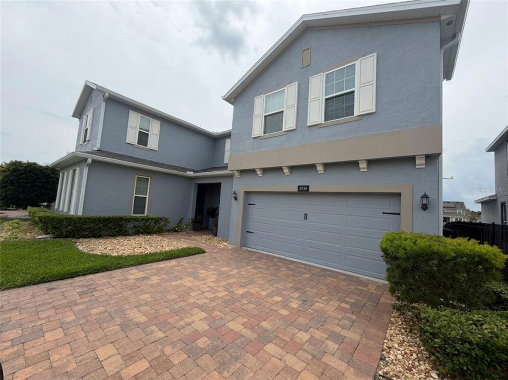 A two-story house with a blue stucco exterior, a two-car garage, and a paver driveway — 4938 CHASE COURT, ST CLOUD, FL