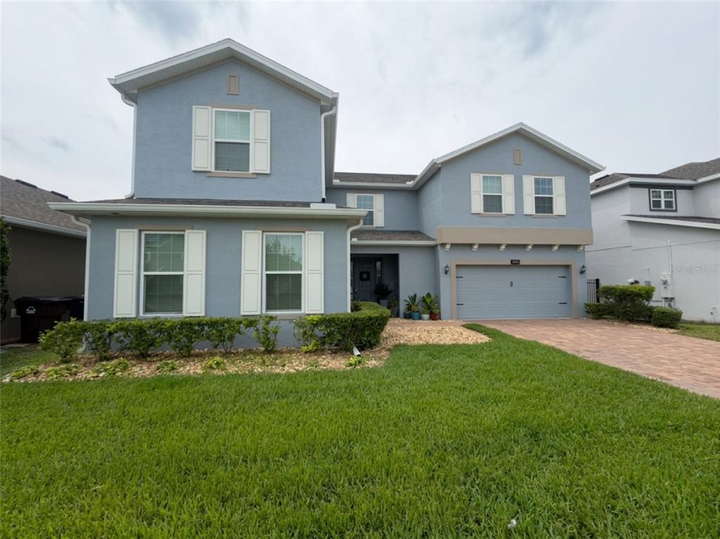 A two-story blue house with white shutters, a two-car garage, and a landscaped front yard — 4938 CHASE COURT, ST CLOUD, FL