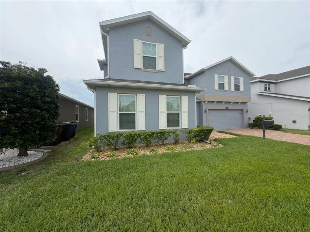 A two-story blue house with white shutters, a garage, and a landscaped front yard — 4938 CHASE COURT, ST CLOUD, FL