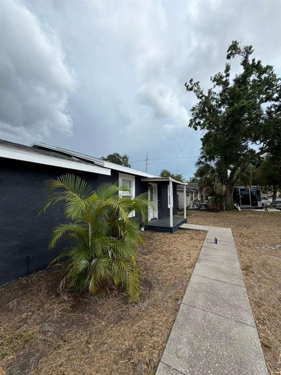 A single-story house with dark gray stucco siding, a white front door, and a gray roof — 6712 S GABRIELLE STREET, TAMPA, FL