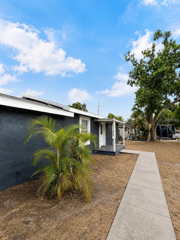 A dark-painted house exterior features a concrete walkway leading to a small covered porch — 6712 S GABRIELLE STREET, TAMPA, FL