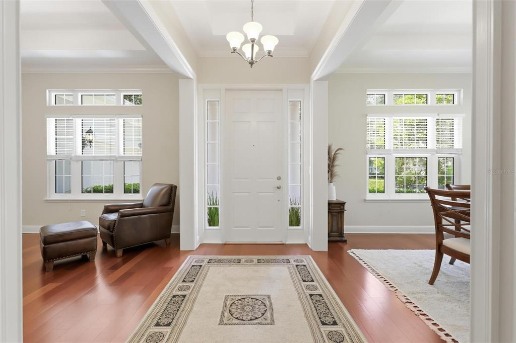 A bright entryway features hardwood floors, a central rug, a white door, and side windows — 300 BELLINGRATH TERRACE, DELAND, FL