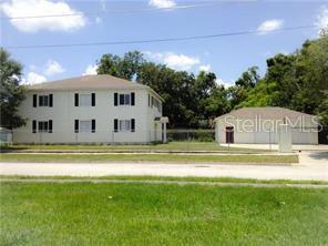 A two-story white building stands next to a detached garage on a grassy lot — 1003 W SUMNER STREET, KISSIMMEE, FL
