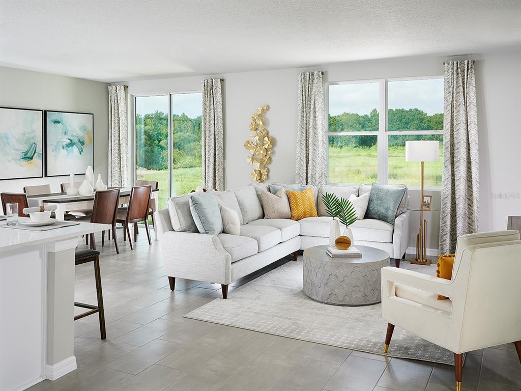 A living room with a sectional sofa, round coffee table, and dining area overlooking greenery — 372 CASTLE DRIVE, LAKE ALFRED, FL
