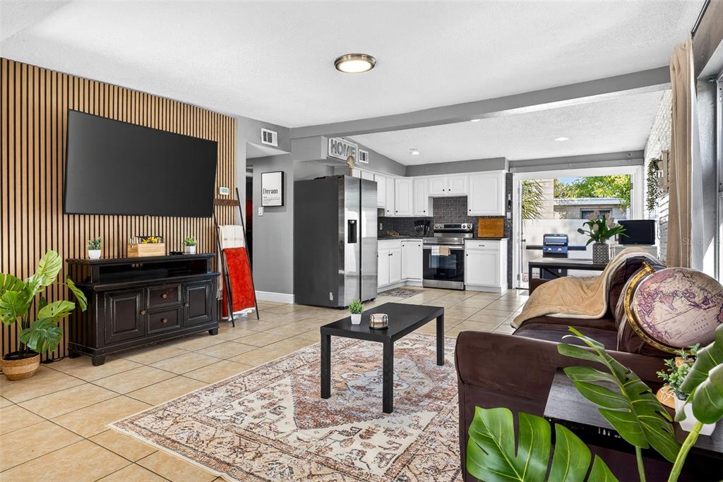 An open-concept living room and kitchen featuring wood-slat wall paneling and tile flooring — 9370 83RD STREET, SEMINOLE, FL