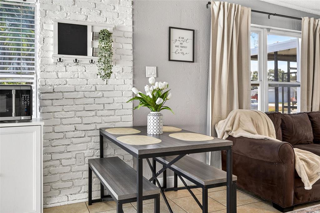 A dining area features a gray table with two benches against a white brick wall — 9370 83RD STREET, SEMINOLE, FL