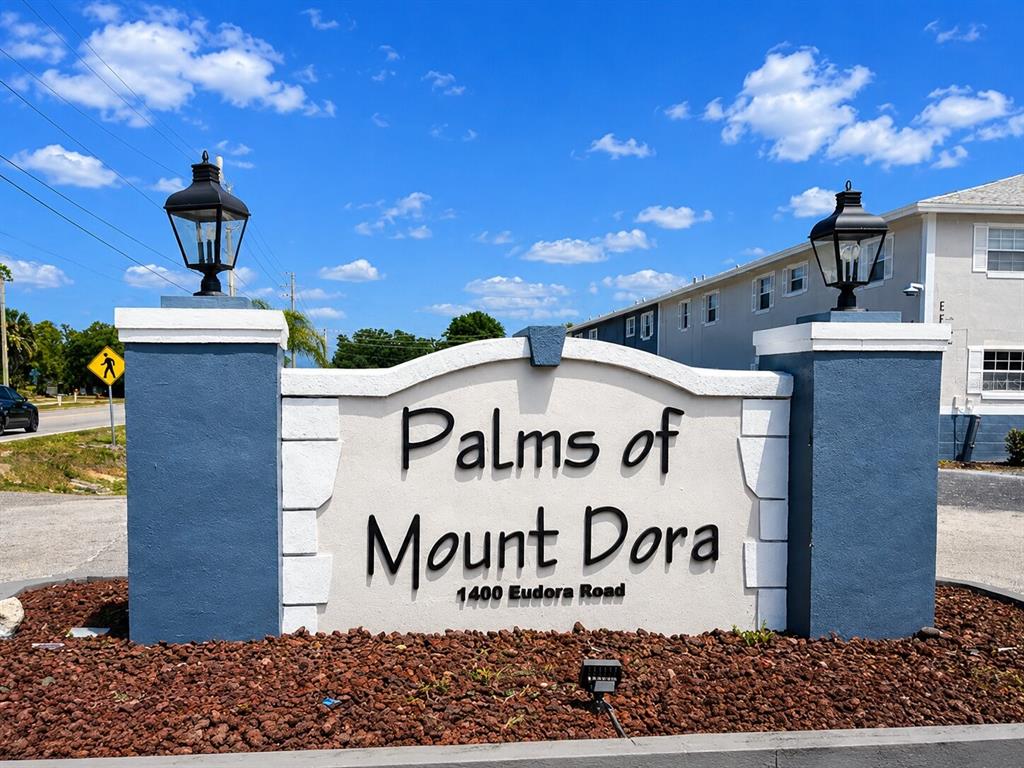 A blue and white monument sign displays the name of a residential community — 1400 EUDORA ROAD UNIT C32, MOUNT DORA, FL