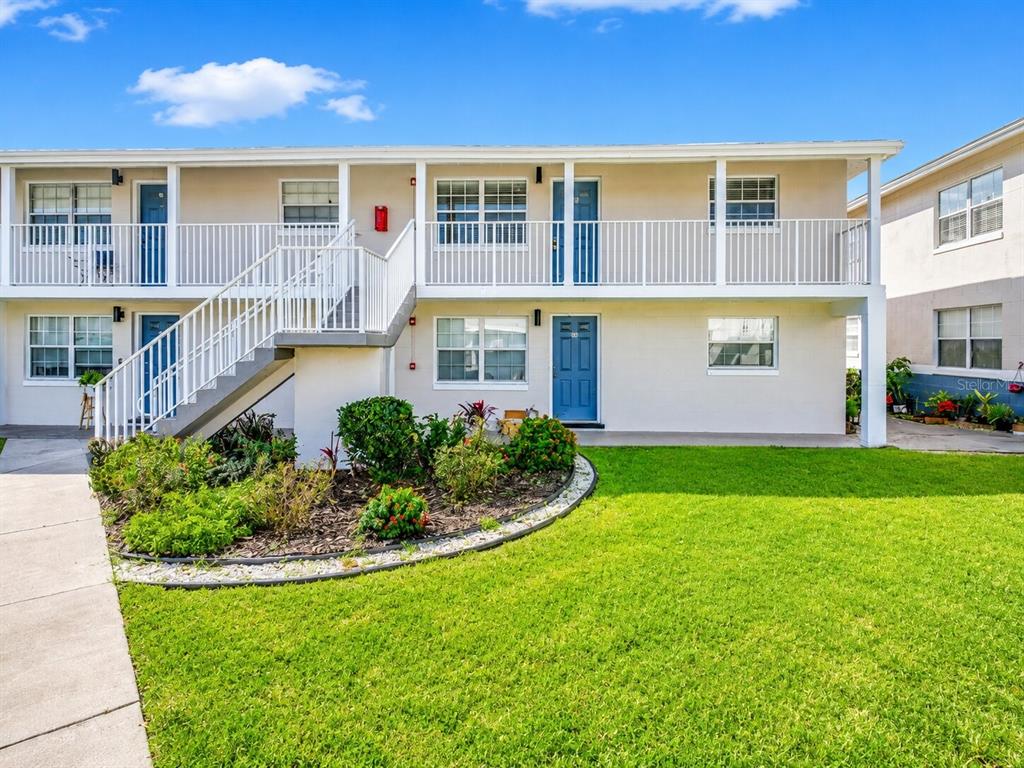 A two-story apartment building with a white exterior, blue doors, and an outdoor staircase — 1400 EUDORA ROAD UNIT C32, MOUNT DORA, FL
