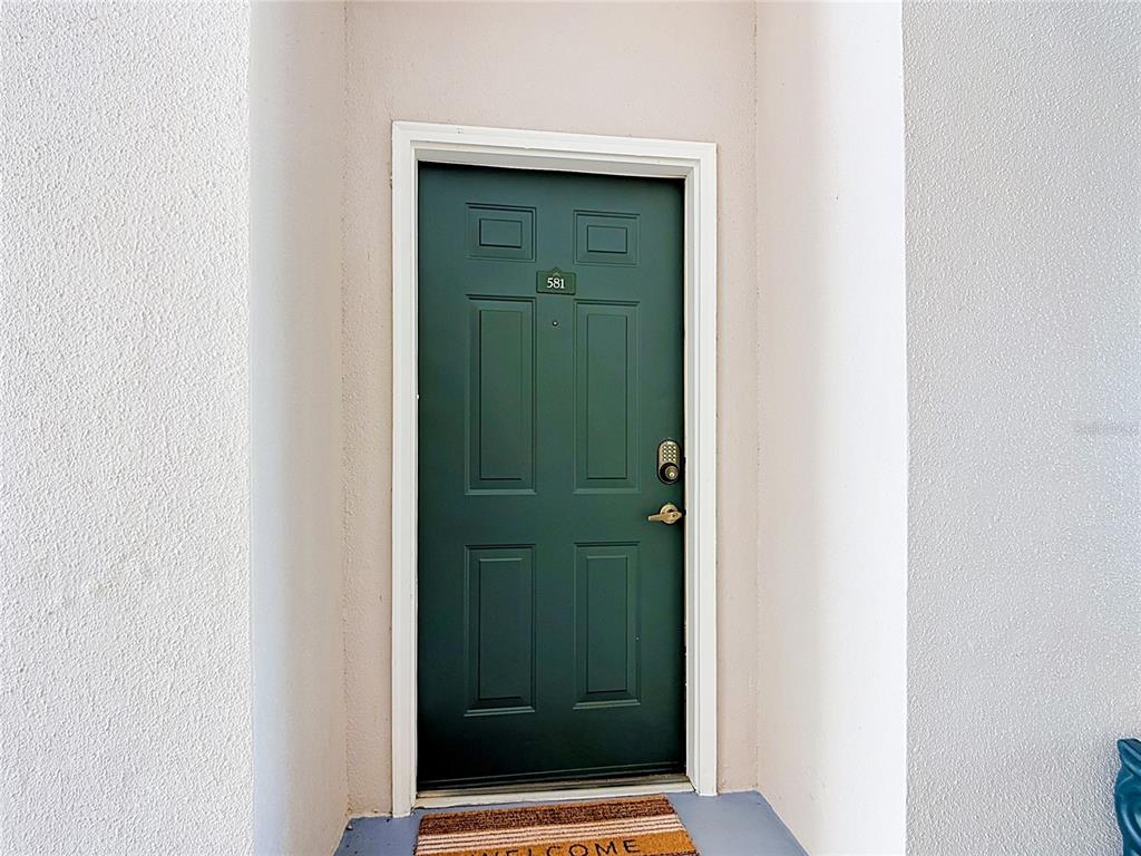 A dark green front door with a number plate is set within a white entryway — 581 WATER STREET UNIT 581, CELEBRATION, FL