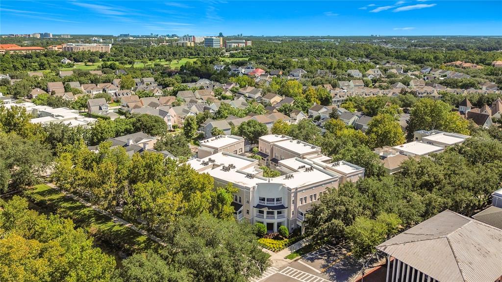 An aerial view shows a multi-story apartment complex surrounded by trees and residential neighborhoods — 581 WATER STREET UNIT 581, CELEBRATION, FL