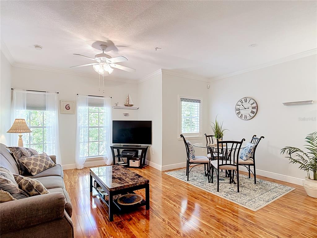A living and dining area features hardwood floors, a ceiling fan, and a wall clock — 581 WATER STREET UNIT 581, CELEBRATION, FL