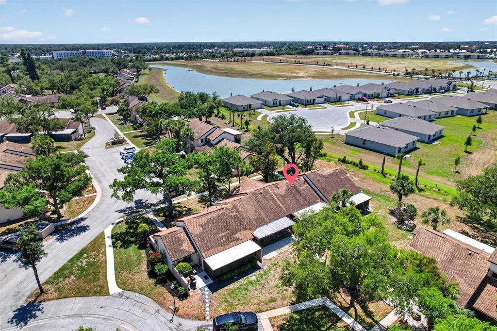 An aerial view shows a residential building with a brown shingled roof near a lake — 5261 BRASSY LOOP, NORTH PORT, FL