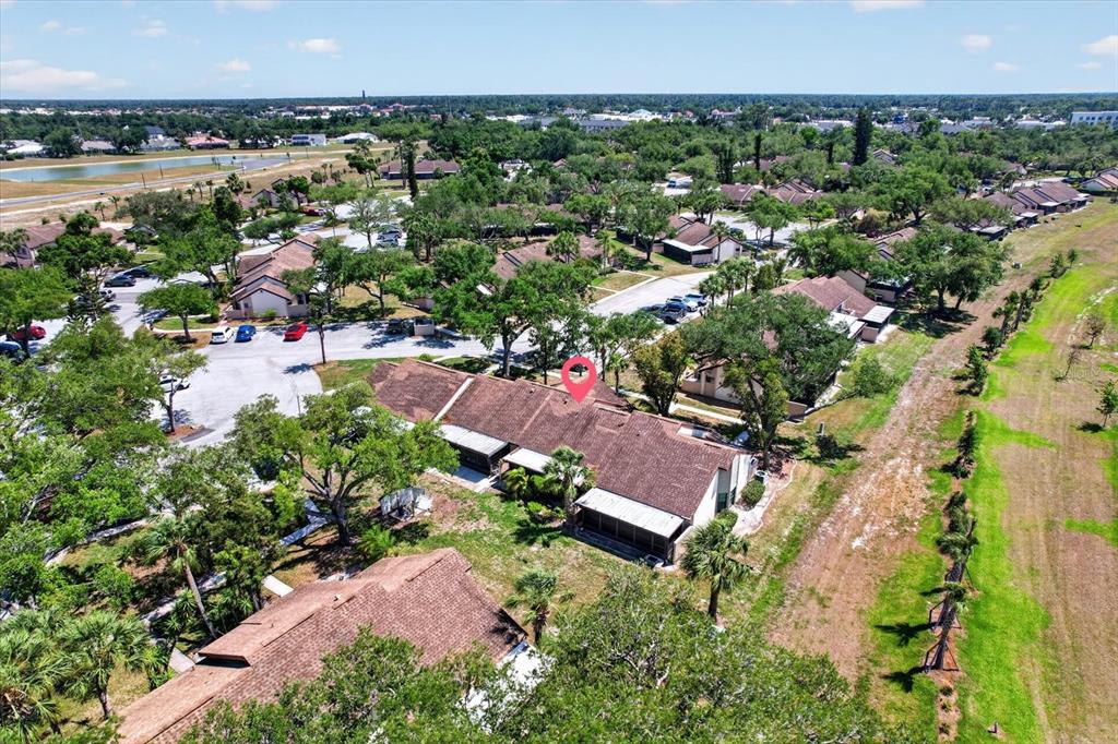 An aerial view shows a residential complex with brown roofs surrounded by trees and grass — 5261 BRASSY LOOP, NORTH PORT, FL
