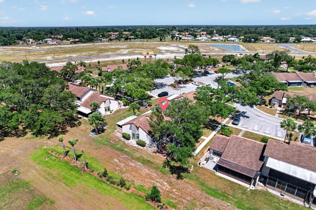 An aerial view shows a residential neighborhood with several houses, trees, and a paved road — 5261 BRASSY LOOP, NORTH PORT, FL
