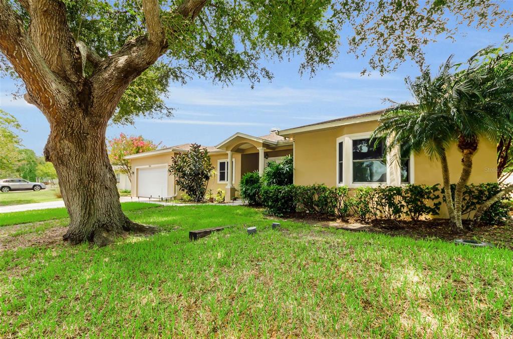 A single-story house with a beige stucco exterior, a white garage door, and double front doors — 1888 BUGLE LANE, CLEARWATER, FL