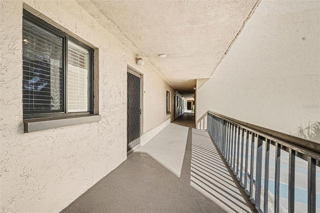 A multi-story apartment building with balconies and a swimming pool behind a black fence — 303 TARPON POINT, TARPON SPRINGS, FL
