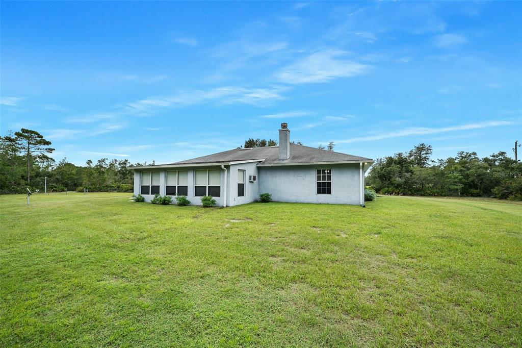 The rear exterior of a single-story house with a screened-in porch and a chimney — 32543 PONDEROSA AVENUE, DELAND, FL